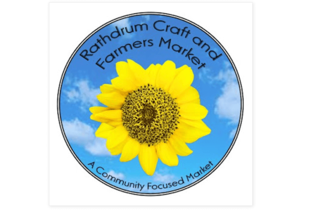 The words Rathdrum Craft and Farmers Market: A Community Focused Market surrounding an image of a yellow flower against a blue sky with white puffy clouds.